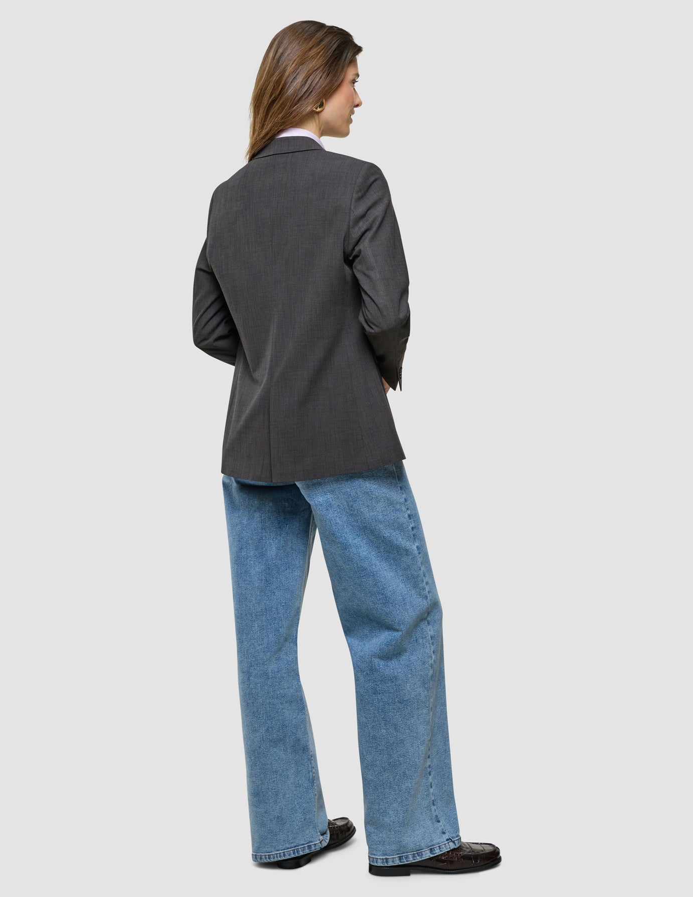 Nara Blazer i Cool Brown, helfigur bagfra af kvinde i grå blazer og blå jeans.